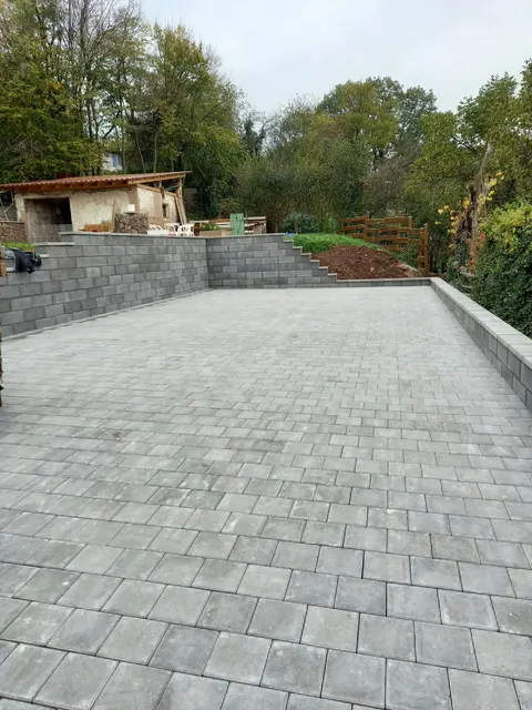 Große gepflasterte Hoffläche mit Stützmauern, gebaut von C&H-Bau