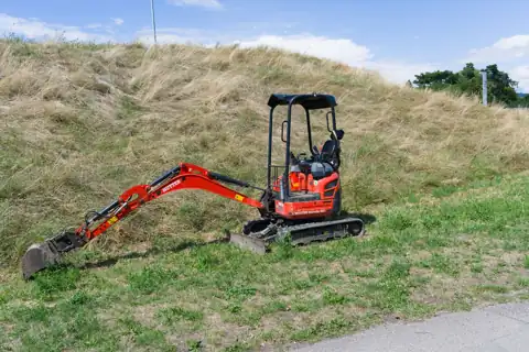Roter Minibagger auf einer Wiese