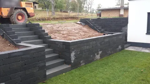 Stützmauer aus anthrazitfarbenen Mauersteinen am Hang, gebaut von C&H-Bau